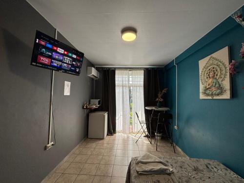 a bedroom with blue walls and a television on the wall at 84Rooms in Cayenne