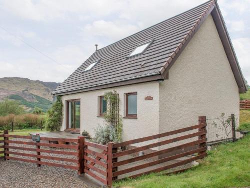 a small house with a wooden fence in front of it at Rosdail in Inverinate