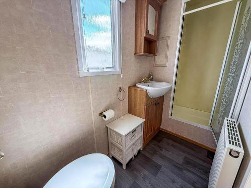 a small bathroom with a toilet and a sink at Great Caravan With Spacious Decking Southview Holiday Park, Skegness Ref 33035V in Skegness