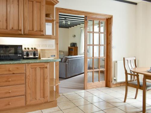 a kitchen with wooden cabinets and a table and a couch at 2 Sawmill Cottages in Puncknowle