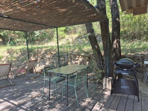 a picnic table and chairs on a deck with a grill at Maisonnette au cœur de la nature in Néoules