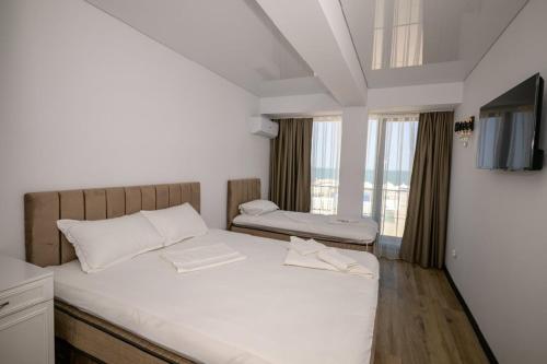 a bedroom with a bed with white sheets and a window at Miraky Beach in Văleni