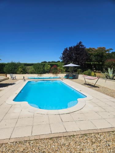 une piscine d'eau bleue et une terrasse dans l'établissement Le Domaine des peupliers, à Saint-Germain-du-Seudre