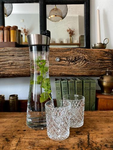 a vase and two glasses on a wooden table at ALTE SCHULE WITTENBERG, 3 Ferienwohnungen für bis zu 12 Personen, an der Elbe, mit Garten in Lutherstadt Wittenberg