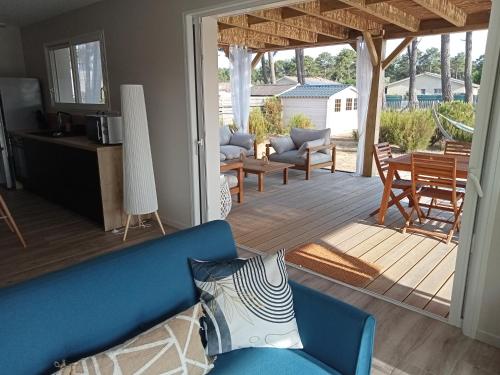 un salon avec un canapé bleu et une terrasse dans l'établissement Santa Monta, à Montalivet-les-Bains