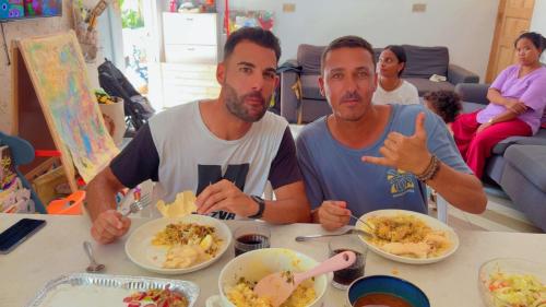 ヒマフューシにあるIsland life Home Stayの二人の男が食べ物を食べて座っている