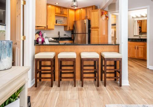 una cucina con mobili in legno e sgabelli da bar di Stay in Abbey Springs 2 BDR with Resort Amenities a Lake Geneva