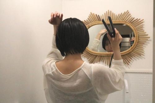 a woman standing in front of a mirror holding scissors at Vacation House Day in Naoshima