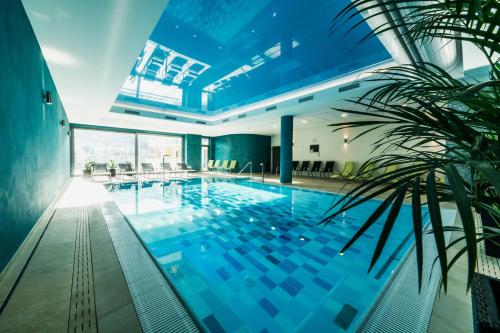 a large swimming pool in a building with a plant at Wellness Hotel Panorama in Trenčianske Teplice