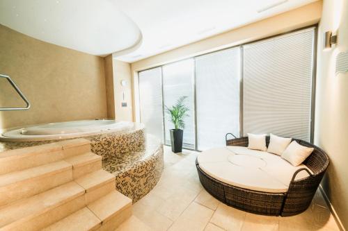 a bathroom with a tub and a chair and a table at Wellness Hotel Panorama in Trenčianske Teplice