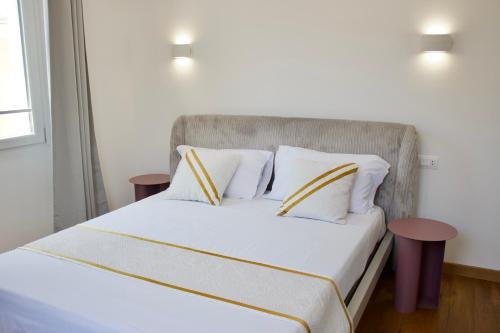 a bedroom with a white bed with yellow and white pillows at Luxenti Luxury Rooms in Cagliari