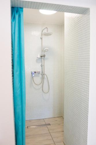 a shower in a bathroom with a blue shower curtain at Pensjonat Lazytown in Pogorzelica