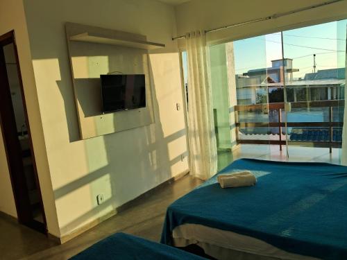 a bedroom with a blue bed and a large window at Pousada Ebenézer, Foguete in Cabo Frio