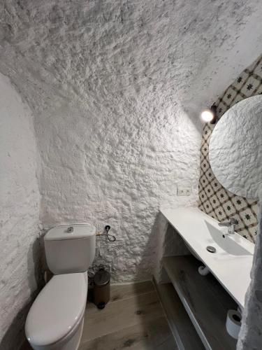 a white bathroom with a toilet and a sink at Cuevas Halima in Bácor