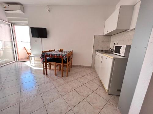 a kitchen with a table and a microwave and a table and chairs at Apartmani Dorana in Vrsi