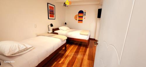 two beds in a small room with wooden floors at Solara Art Hotel by Amak in Cusco