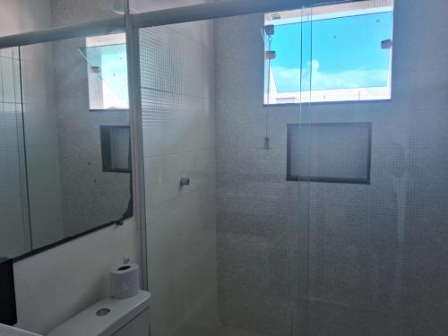 a bathroom with a glass shower with a toilet and a window at Pousada Ebenézer, Foguete in Cabo Frio