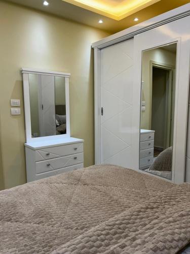 a bedroom with a bed and a dresser and a mirror at marhaba madinaty 34 in Madinaty