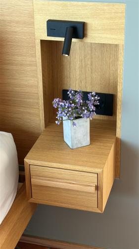 a wooden shelf with a pot of purple flowers on it at Maison Meltem in Agia Pelagia