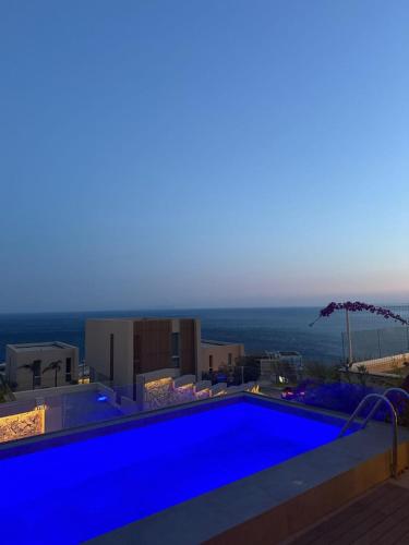 a blue swimming pool with the ocean in the background at Calma View Apartment Green Coast in Palasë