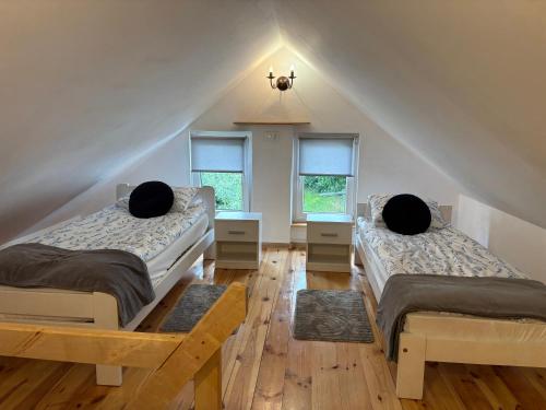 a attic room with two beds and two windows at Urocze Roztocze Jacnia - domek 2 in Jacnia