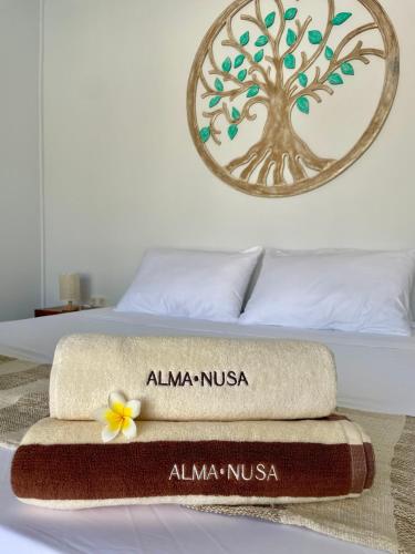 a bed with a towel on it with a tree on it at Alma Nusa Penida in Nusa Penida