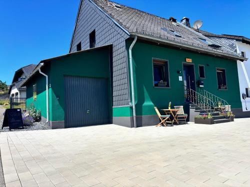a green building with a garage and a patio at harmony holiday, Pension in Kerschenbach