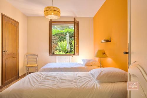two beds in a room with a window at Maison de la Rade, sea view and air conditioning in Saint-Mandrier-sur-Mer
