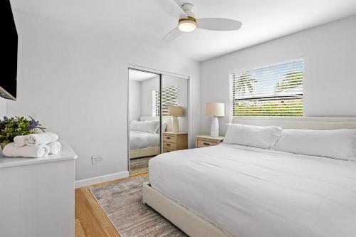 a white bedroom with a bed and a mirror at Hot Tub Salt Pool Png Png 5 Min to AtlAv Trampline in Delray Beach