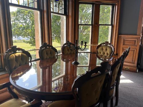 a dining room with a glass table and chairs and windows at The Royal Tay Apartment in Dundee