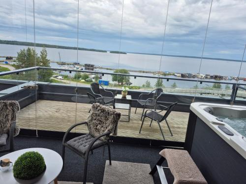 a balcony with chairs and a view of the water at TAMPERE PENTHOUSE-tasokas moderni kaupunki huoneisto huipulla -ISO JACUZZI omalla KATTOTERASSILLA - AURINKOTUOLIT ja Aurinko odottaa Sinua - huikea maisema- - 10 HLÖ - free parking in Tampere