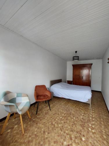 ein Schlafzimmer mit einem Bett und einem Stuhl darin in der Unterkunft Maison de pêcheur - Quartier Croix de Vie in Saint-Gilles-Croix-de-Vie