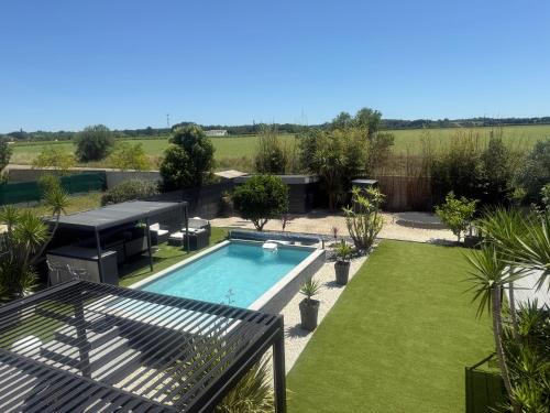 une grande arrière-cour avec piscine et pelouse dans l'établissement Villa de standing avec piscine et climatisation, à Caissargues
