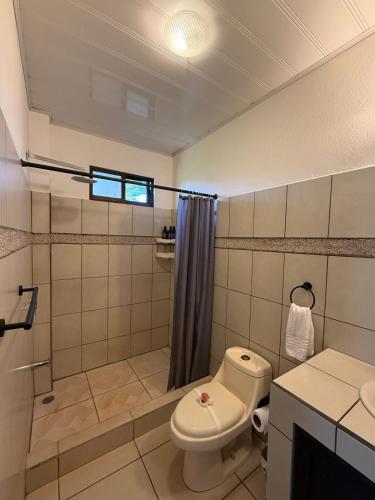 a bathroom with a toilet and a shower and a sink at Villa Macaw in Parrita