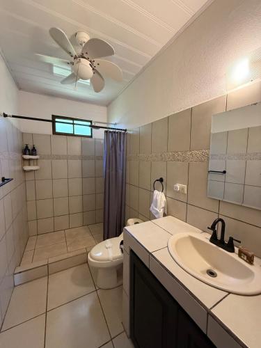 a bathroom with a toilet and a sink and a ceiling fan at Villa Macaw in Parrita