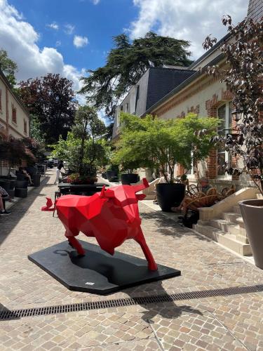 a statue of a red bull on a sidewalk at Champagne André Bergère & Suites in Épernay