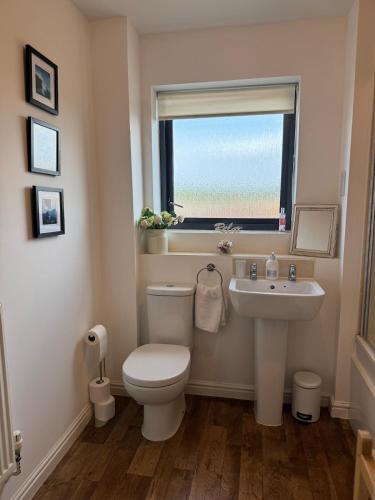 a bathroom with a toilet and a sink and a window at Uxbridge-Modern 2 bed Apt with Lift & Parking in Uxbridge