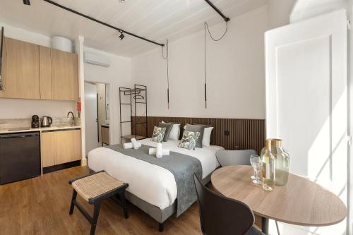 a bedroom with a bed and a table and a kitchen at Solar das Termas in Caldas da Rainha