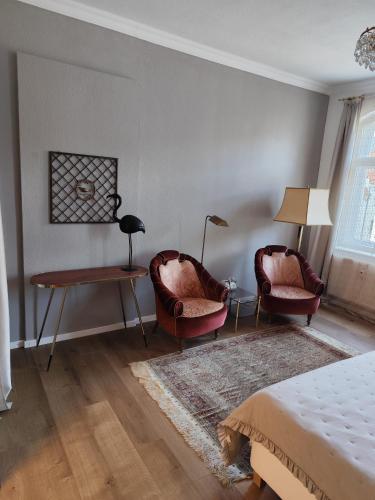 a bedroom with two chairs and a table and a bed at Alberthof Zittau in Zittau