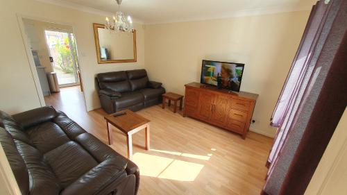 a living room with a leather couch and a television at Beautiful 3 bedroom House Manchester in Little Hulton