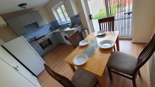 a dining room table with chairs and a kitchen at Beautiful 3 bedroom House Manchester in Little Hulton