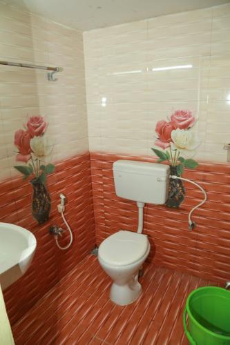 a bathroom with a toilet and a sink and flowers at Sky Touch Inn in Yercaud