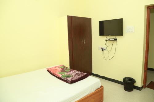 a bedroom with a bed and a tv on a wall at Sky Touch Inn in Yercaud