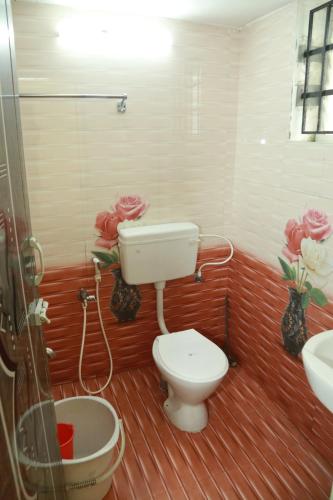 a bathroom with a toilet and a sink and flowers at Sky Touch Inn in Yercaud