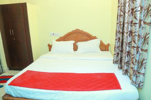 a bedroom with a bed with a red blanket on it at Sky Touch Inn in Yercaud