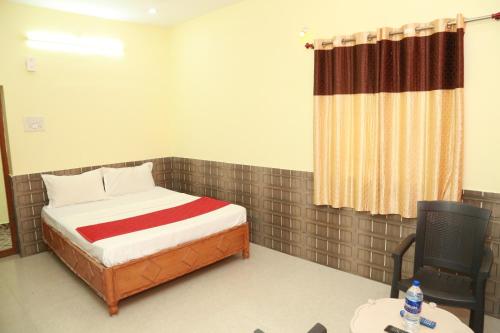 a small bedroom with a bed and a chair at Sky Touch Inn in Yercaud