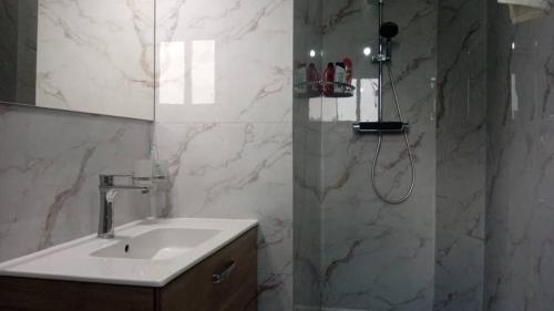 un bagno con lavandino e doccia con specchio di Le Conviviall a Yaoundé
