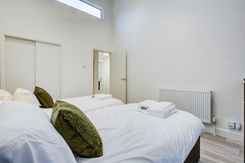 1 Schlafzimmer mit 2 Betten mit weißer Bettwäsche und grünen Kissen in der Unterkunft Sleek 3 Bedroom 6 Beds 2 Bath Home in Colchester