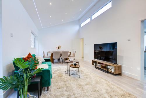 a living room with a green couch and a tv at Sleek 3 Bedroom Home Sleeps 6 with Parking in Colchester