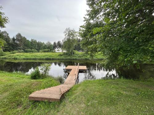 a wooden bridge over a small pond in a park at MyHouse Silla Pärnu Holiday House in Silla